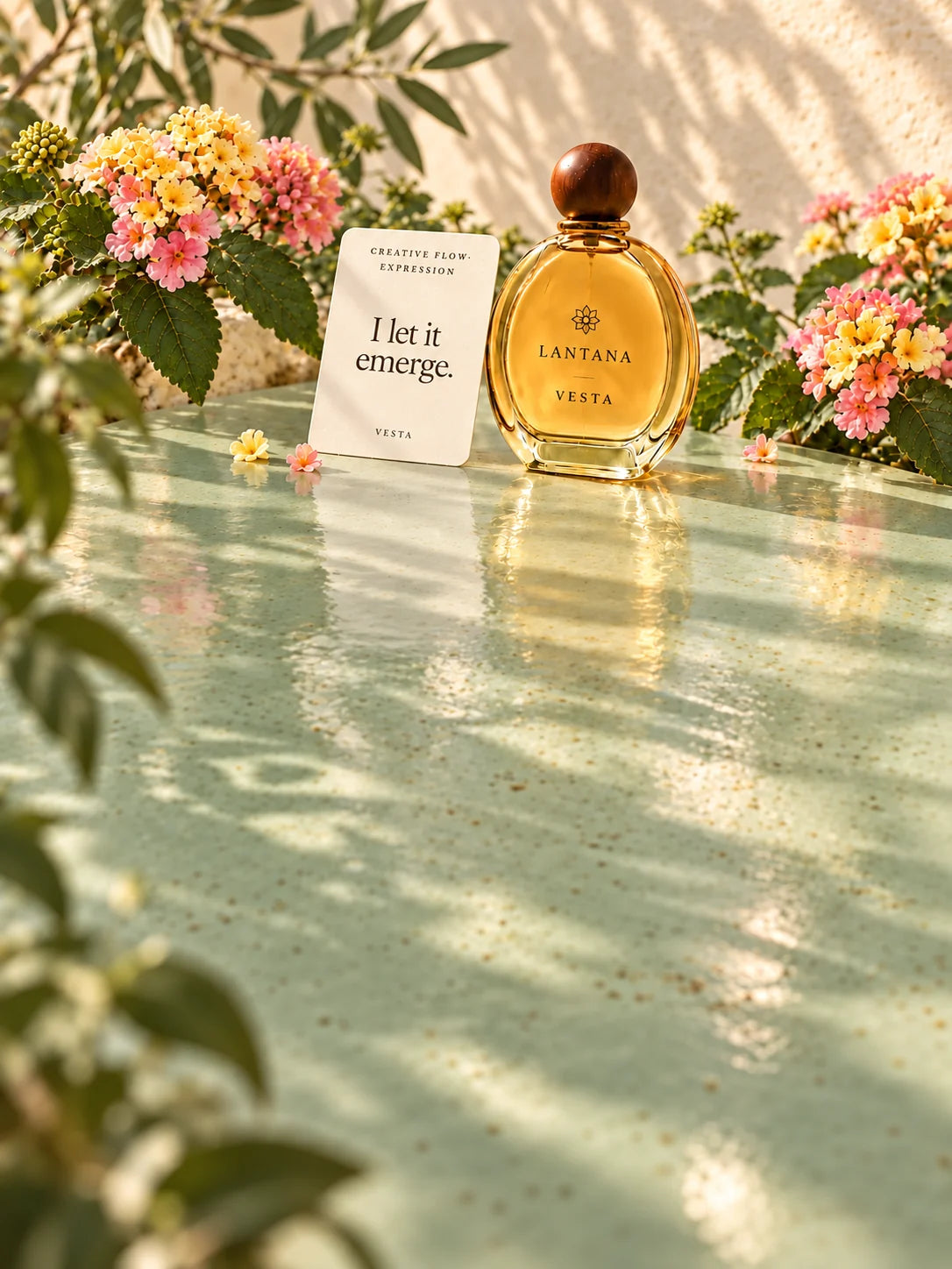 VESTA perfume bottle and its Creative Flow and Expression intention card with pastel lantana reflected in pale sage glazed ceramic.