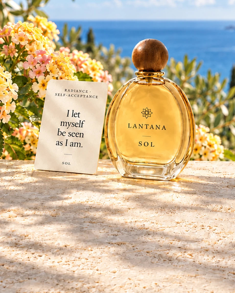 SOL perfume bottle and its Radiance and Self-Acceptance intention card with pale yellow lantana on a sunlit terrace overlooking the Mediterranean.