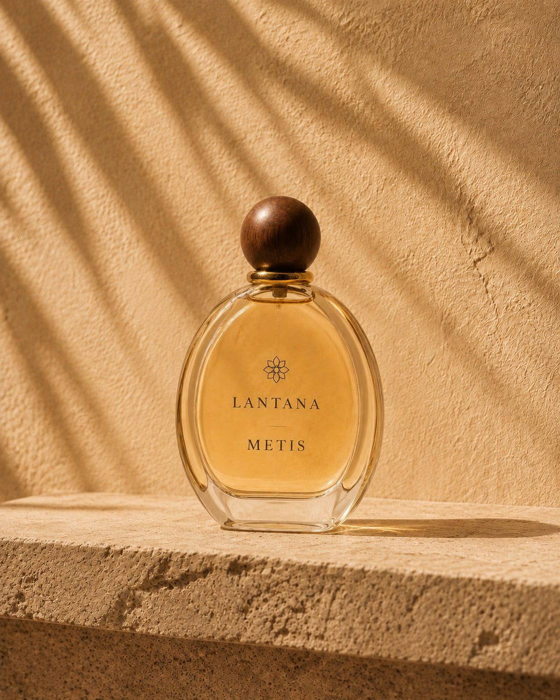 An amber METIS perfume bottle with a round wooden cap, held in an organic frame.